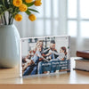 Acrylic photo block with a family photo on a wooden surface with yellow tulips and books.