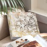 Photo album with gold foil butterfly design on a surface next to an open album