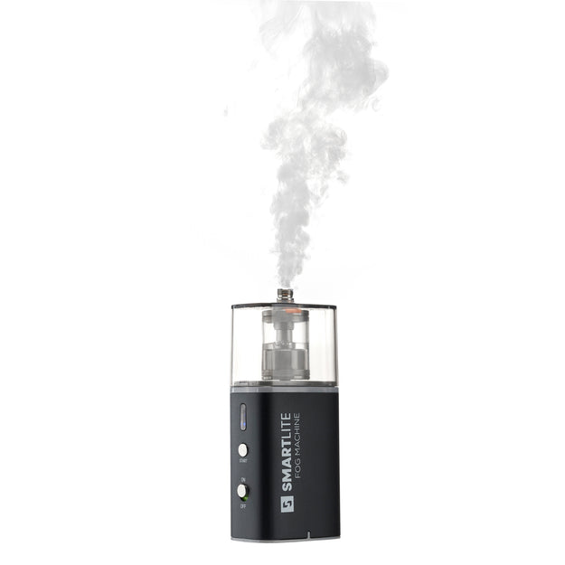 Black fog machine device with SmartLite branding emitting white smoke on a white background